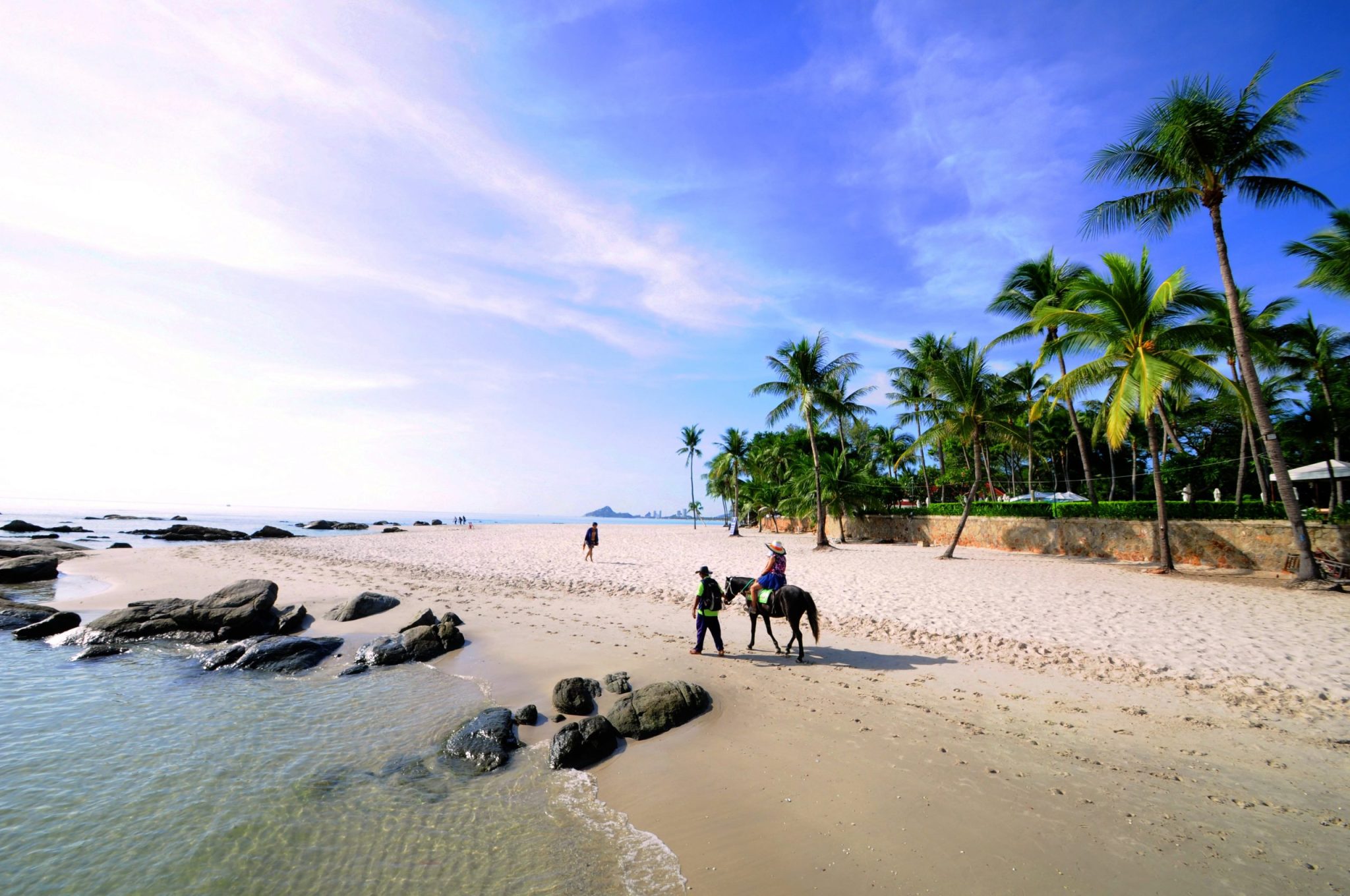 A holiday-goer enjoys a horseback ride along Hua Hin beach.