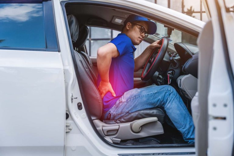 A man experiences lower back pain after driving.